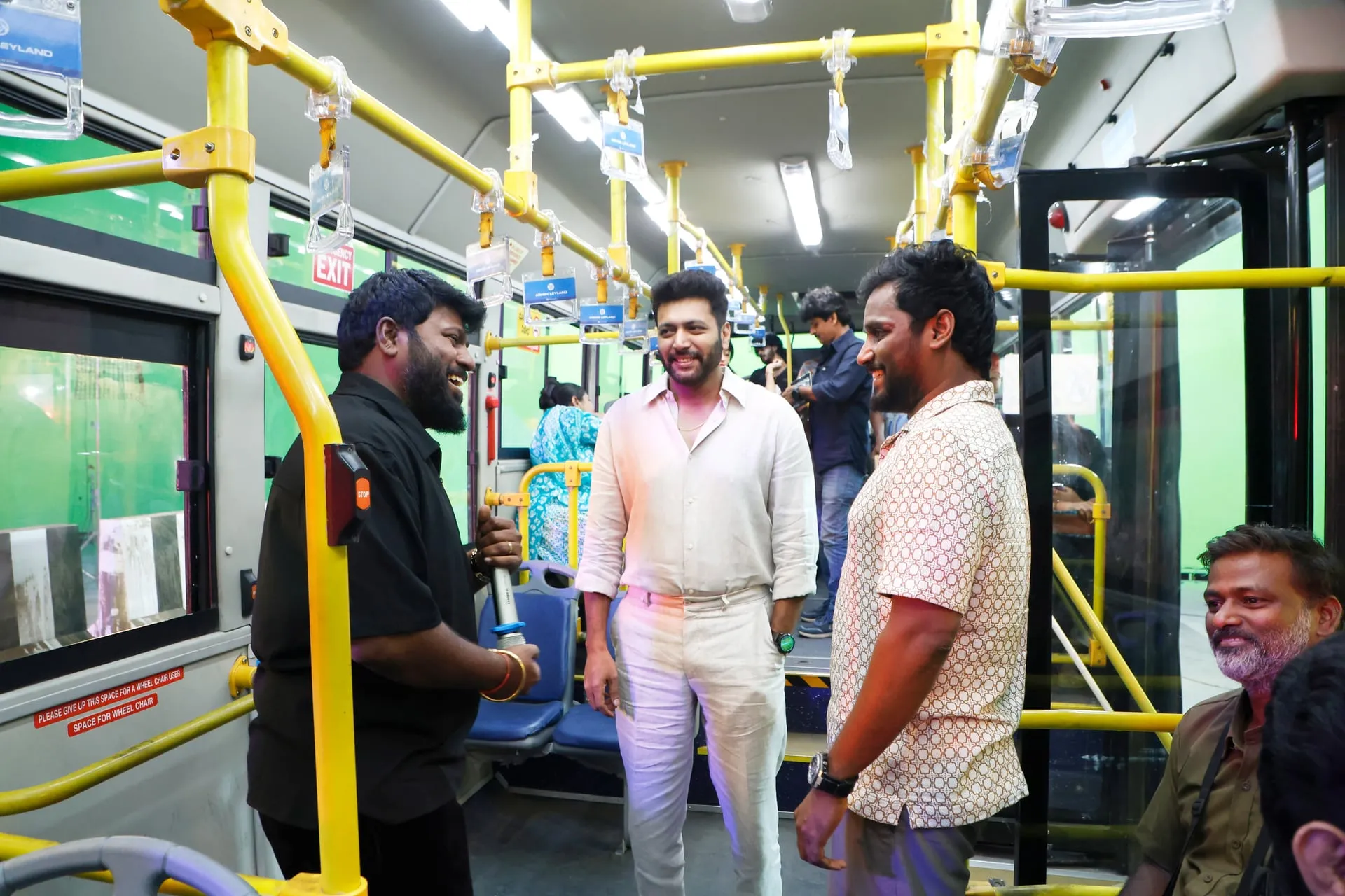 Ravi Mohan on a film set, smiling between two crew members