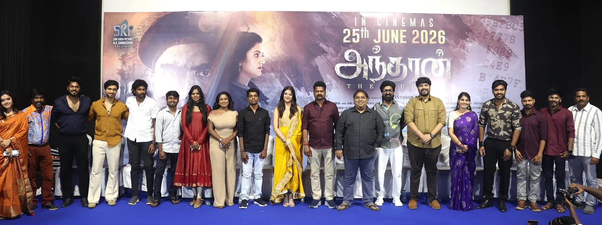 The Andharan cast and crew on stage in front of the film's poster announcing a June 25, 2026 release