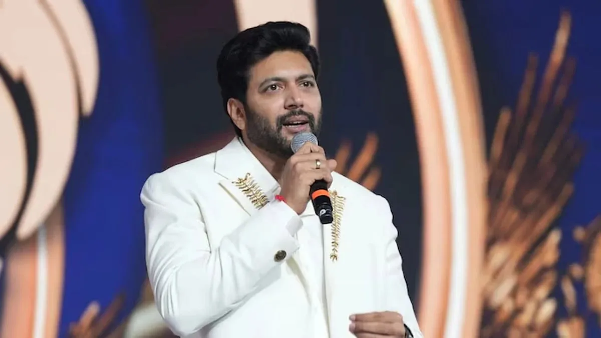 Ravi Mohan in a white embroidered suit speaking into a microphone at a JFW awards event in Chennai