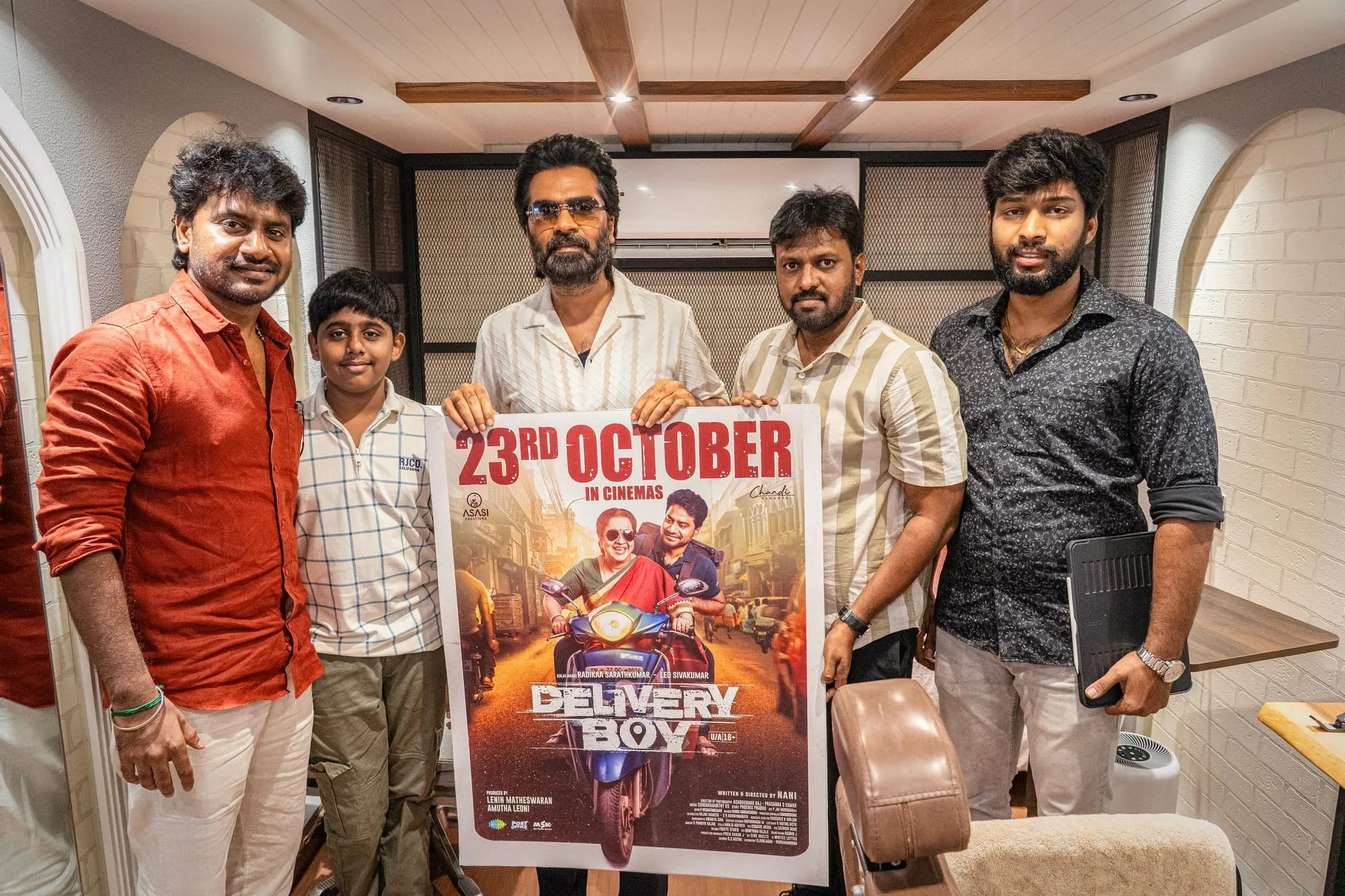 Silambarasan TR holds the Delivery Boy release poster with Leo Sivakumar and members of the film's team