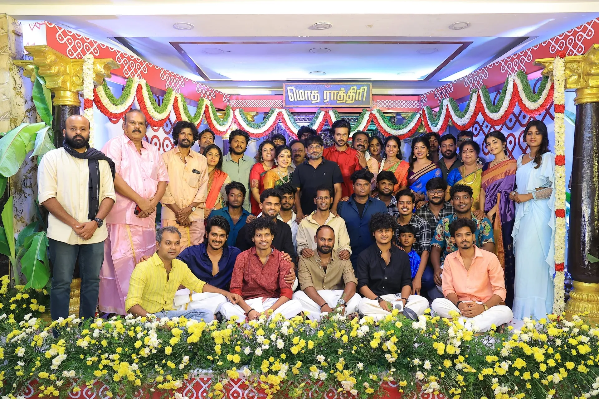 Modha Rathri team group photo at the trailer launch with the film's title board overhead