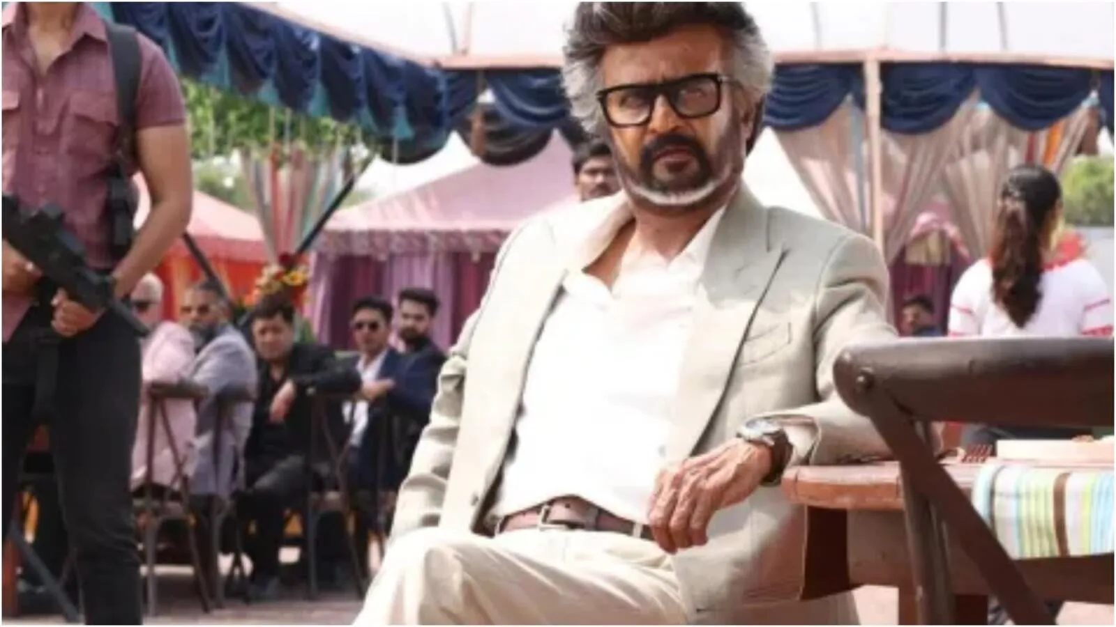 Rajinikanth in a cream suit sits under a canopy, with armed guards behind him, in a Jailer 2 still