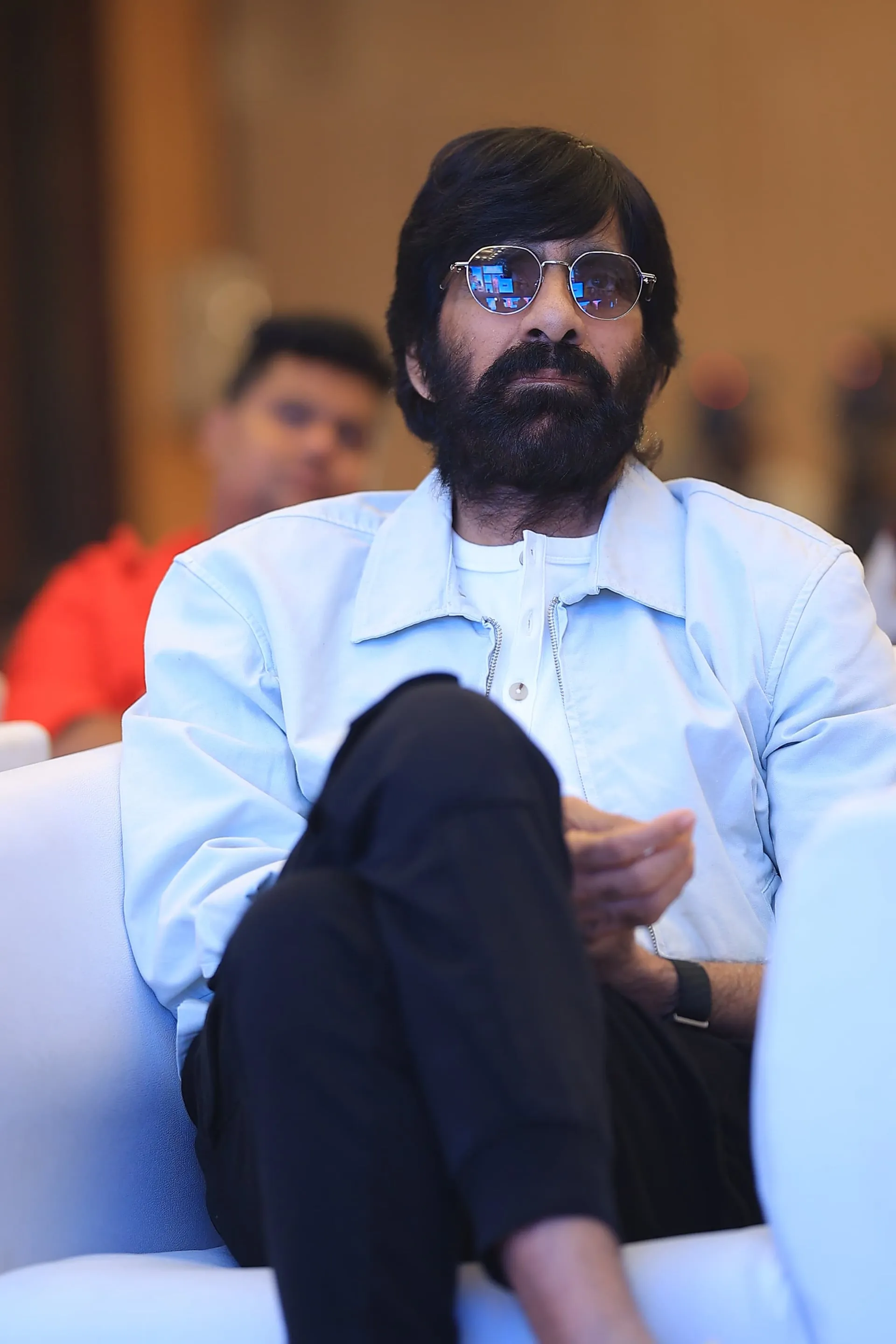 Ravi Teja seated in the front row in a pale blue jacket and sunglasses