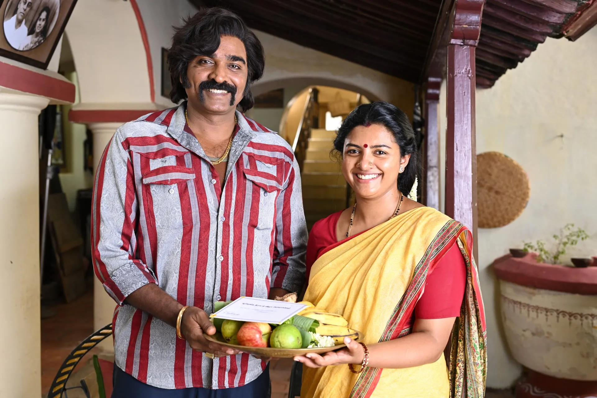 Striped shirt, gold chain and a grin: Baththa at his most neighbourly, with Kannima beside him
