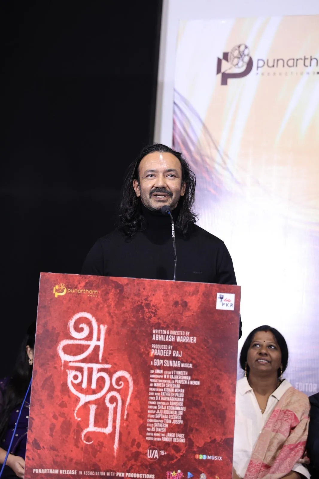A guest speaks at the podium during the Aroopi trailer and music launch