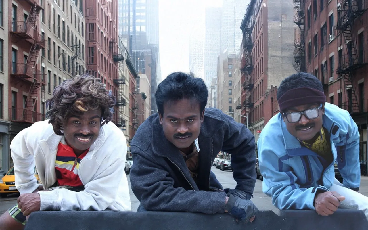 Three Rajkumar characters leaning over a barrier on a deserted Manhattan street